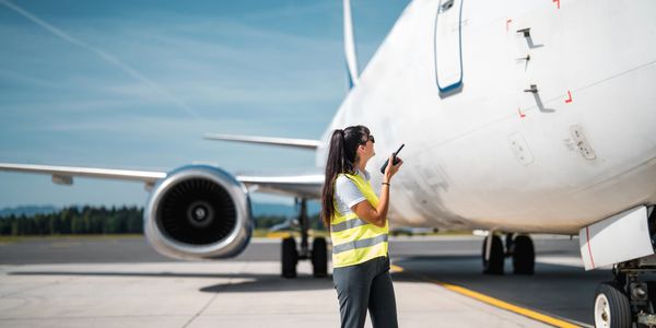 Airport ground staff communicating near a parked airplane.aviation safety
engineering standards
skilled technicians