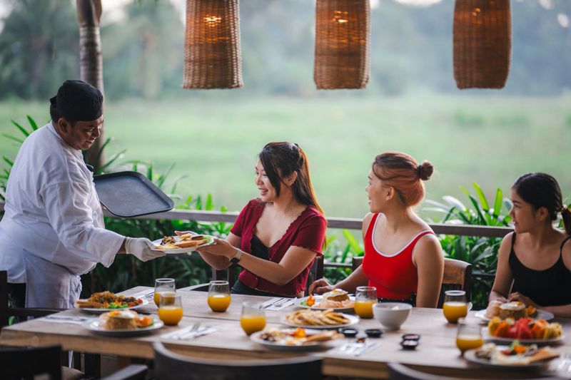A private chef at the villa serves a meal to three female guests, highlighting authentic local flavors