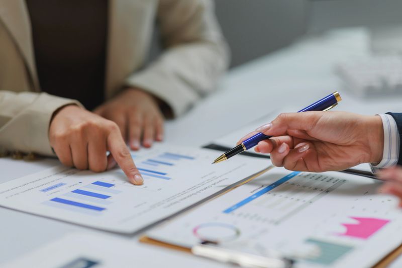 Businesswomen pointing at charts and discussing financial data during a productive office meeting