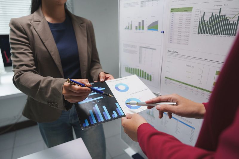 Businesswomen analyzing financial data, pointing at charts and graphs during a productive office meeting