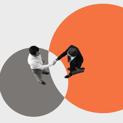 Two businessmen shaking hands over overlapping circles.