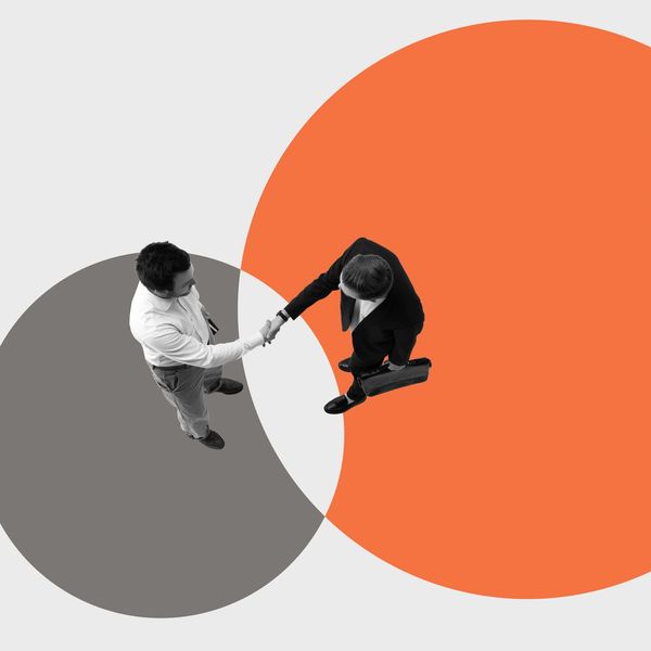 Two businessmen shaking hands over overlapping circles.