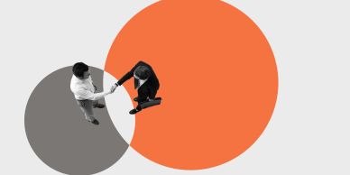 Two business people shaking hands over overlapping circles, symbolizing partnership.