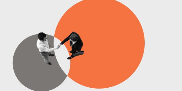 Two businessmen shaking hands with overlapping colored circles beneath them.