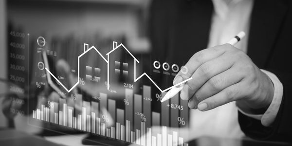 Person analyzing real estate market trends with digital graphs.
