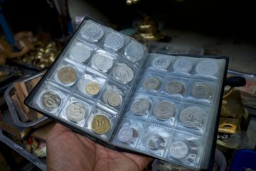 A hand holding a coin collection album with various coins.