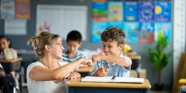 Teacher assisting children in a supportive classroom setting.