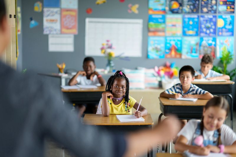 Young students from diverse backgrounds actively participating in a colorful and engaging classroom. The atmosphere promotes learning and inclusivity, showcasing collaboration and enthusiasm among children and educators.