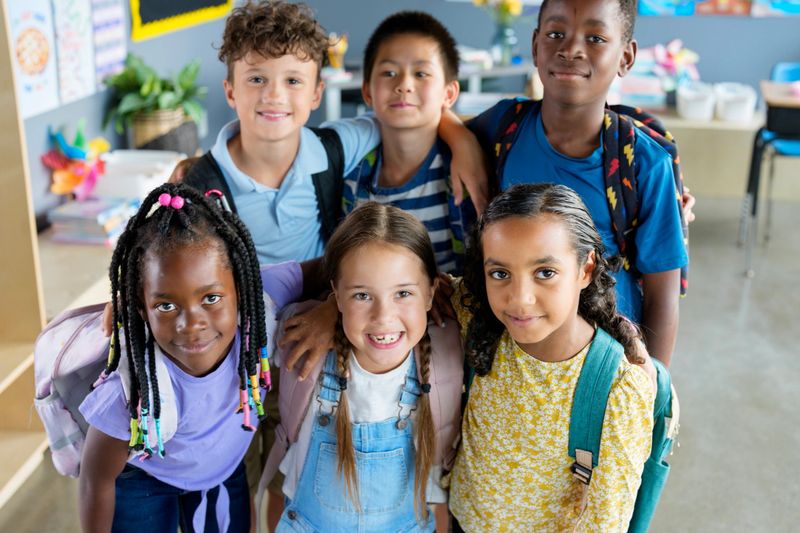 Happy group of children posing with friends in a lively classroom setting, celebrating diversity and togetherness at school.