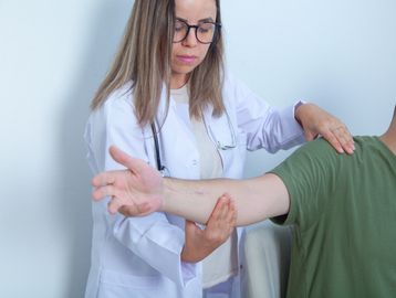 Doctor examining patient's arm with care and focus.
