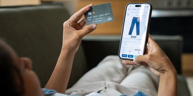 Person looking at phone while holding credit card