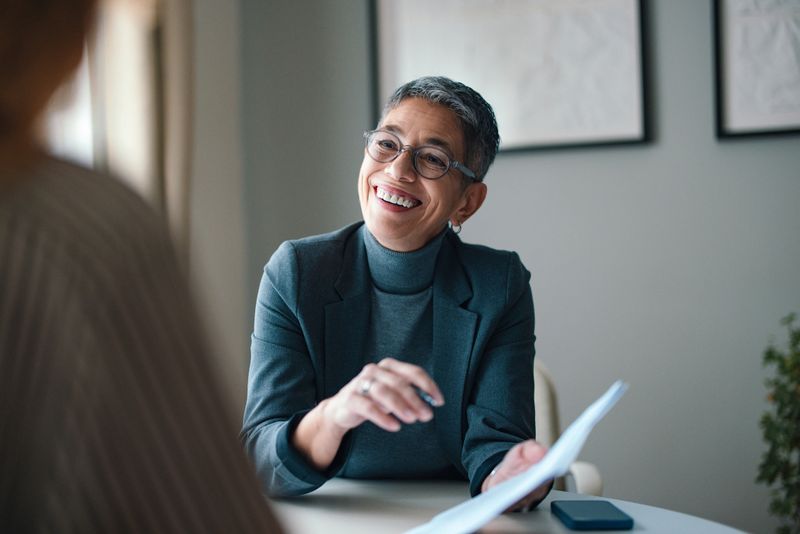 Professional woman smiling during a business conversation in a modern office setting.