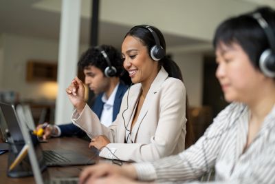 Three people working with headsets in an office.