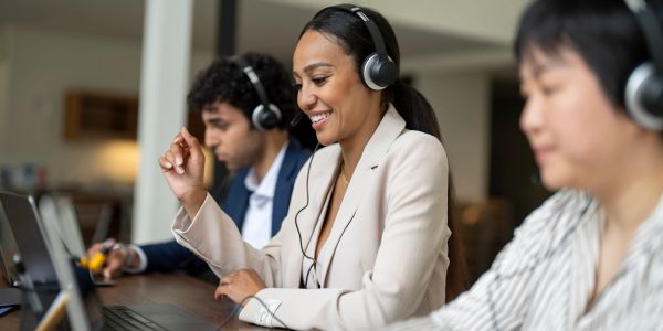 Diverse customer service team wearing headsets and working on laptops.