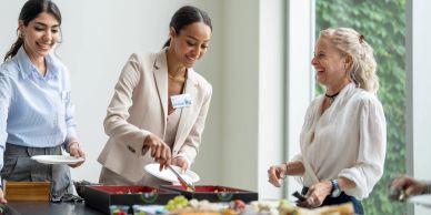 Three women enjoying food together at an event.