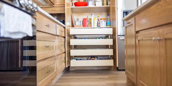 Wooden kitchen drawers open with spices and food items.