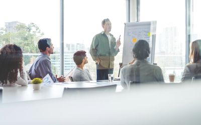 A man presents ideas to colleagues during a meeting in a bright office.