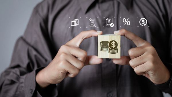 Person holding a block with a money symbol and financial icons above.