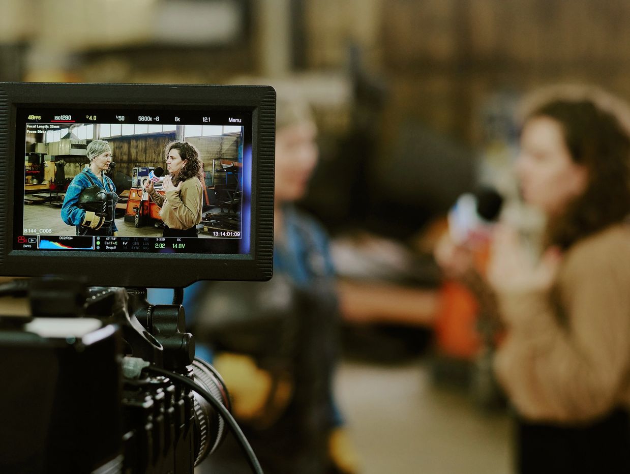 Two women are recorded during an interview with boxing gloves in an industrial setting.
