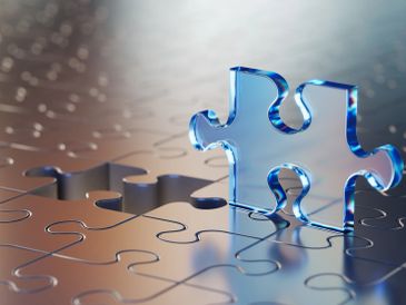 A transparent blue puzzle piece about to fit into its spot on a reflective puzzle.