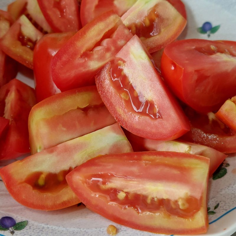 Ripe red tomatoes sliced into pieces, ready for cooking or salad preparation.