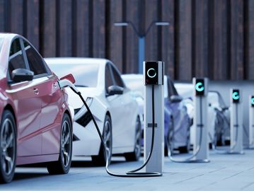 Electric cars charging at a row of charging stations.