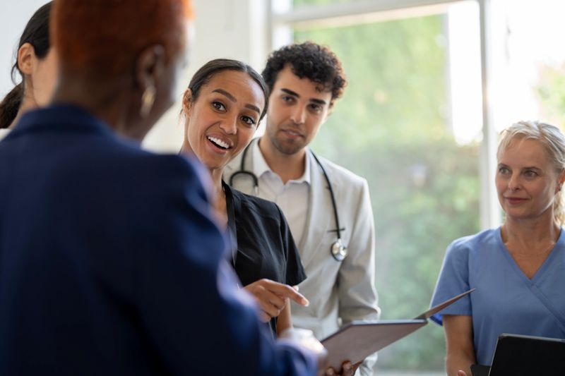 Healthcare providers sharing ideas and updates in a collaborative environment, featuring a diverse group of professionals working together for patient care.