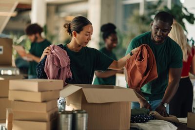 Volunteers sorting clothes and packing boxes in a donation center.
