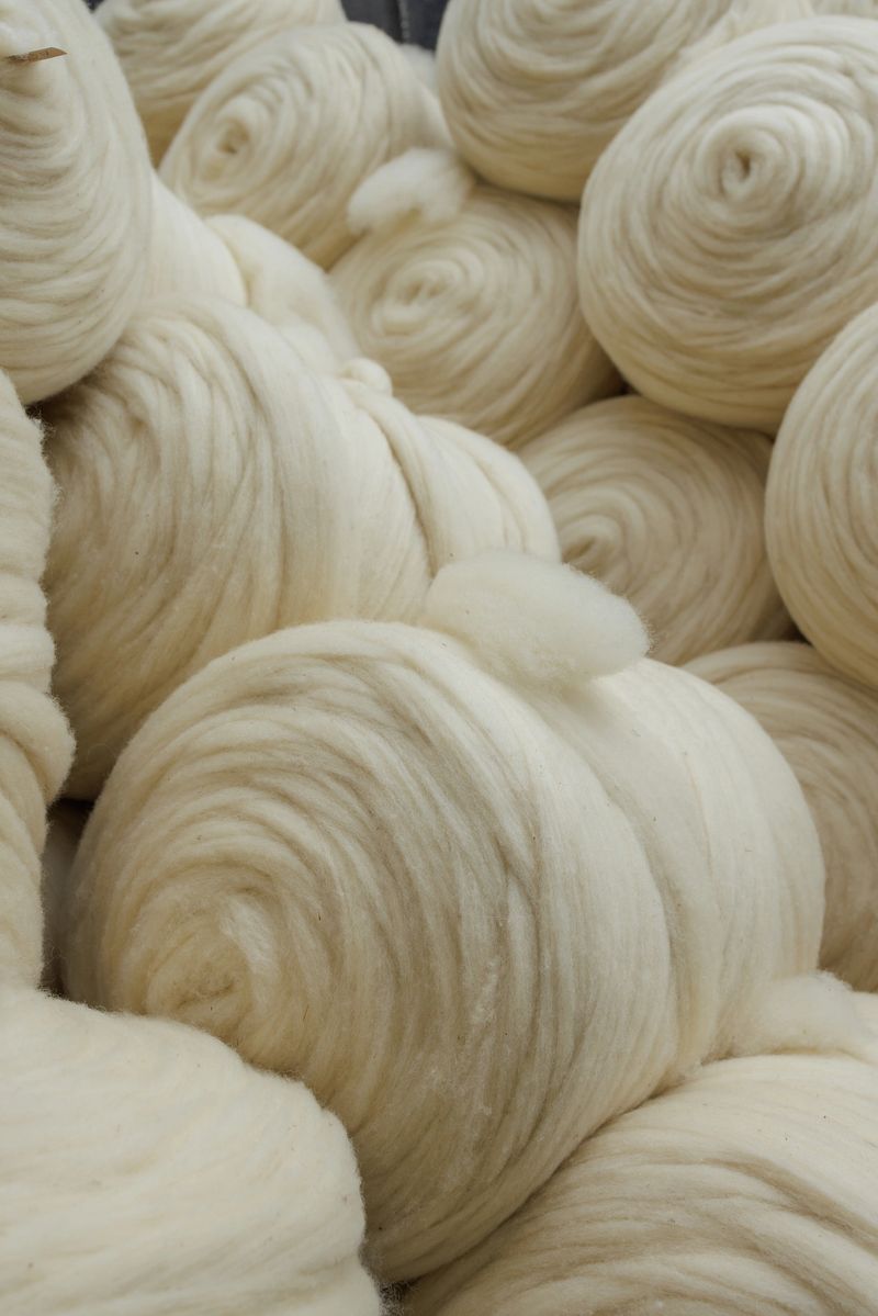 Undyed wool sliver coils stacked in a textile mill, showing clean natural fiber processing for yarn and sustainable production.
