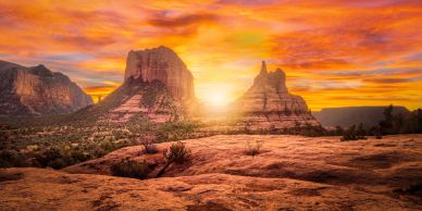 Sunset over rocky desert mountains with vibrant orange sky.