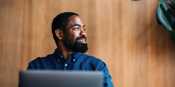 Man smiling while looking away from his laptop.