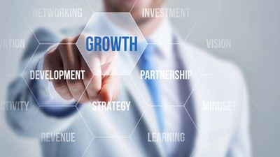 Man in a business suit pointing to a hex shape with the word growth in it, next to others with devel