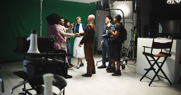 Film crew greeting an actor dressed as a nun on set.