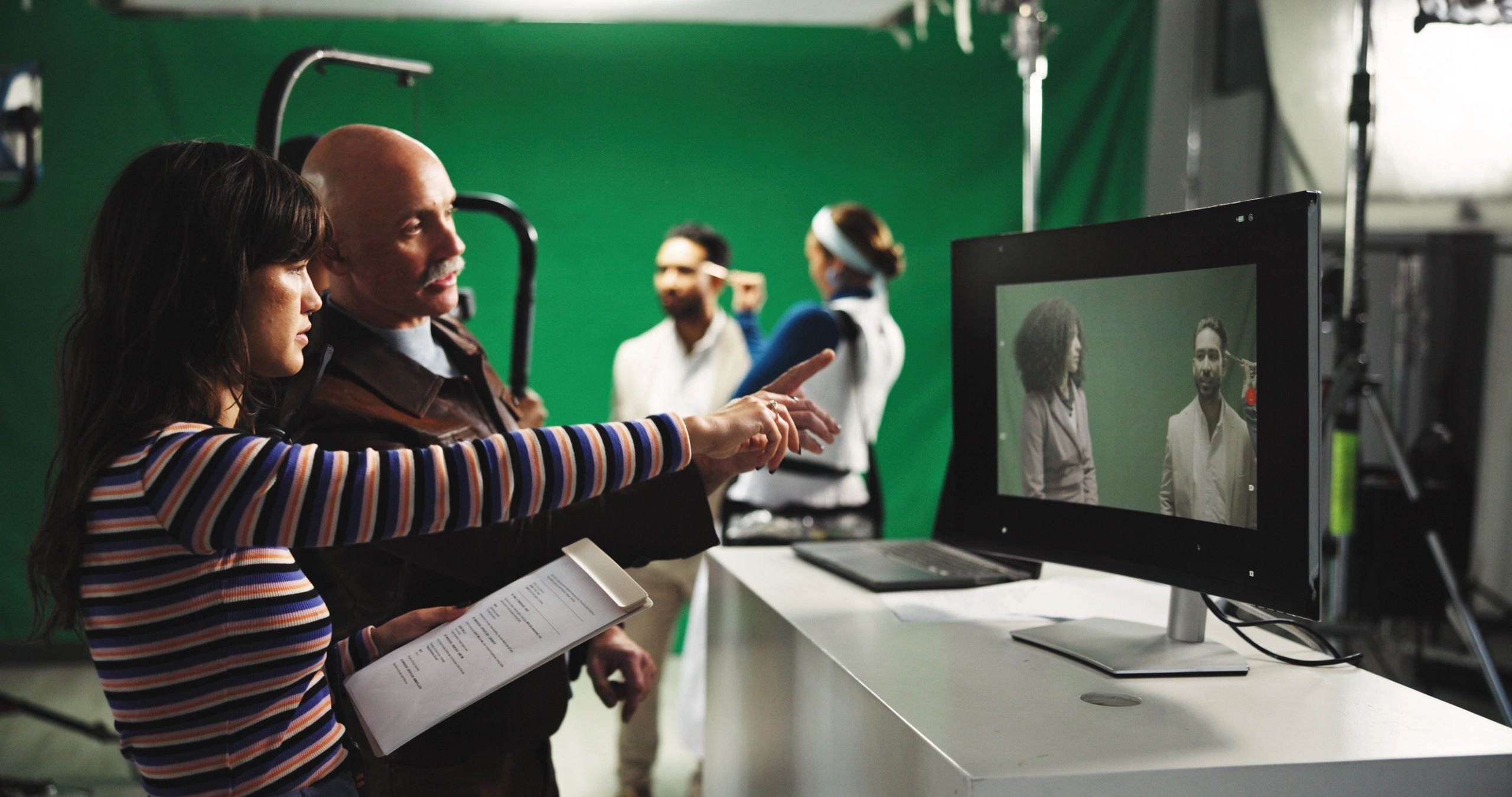Director and assistant director looking at a monitor on a green screen film set