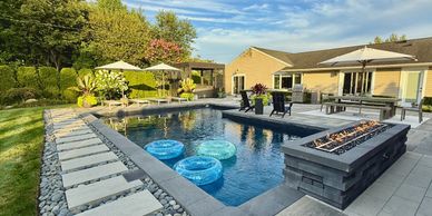 Modern backyard pool with fire pit and seating area.