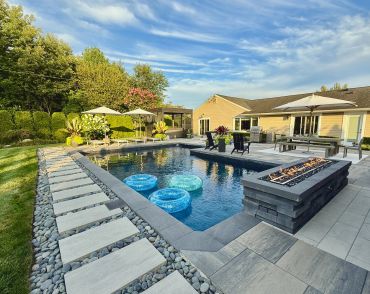Backyard pool with fire pit and lounge chairs.