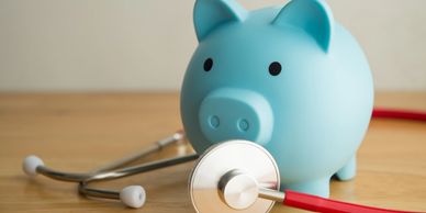 Blue piggy bank with a stethoscope on a wooden surface.