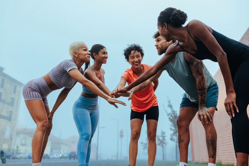 Group of athletes joining hands after a successful workout session outdoors, demonstrating teamwork, motivation, and fitness