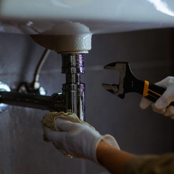 Plumber's hands repairing a sink pipe.