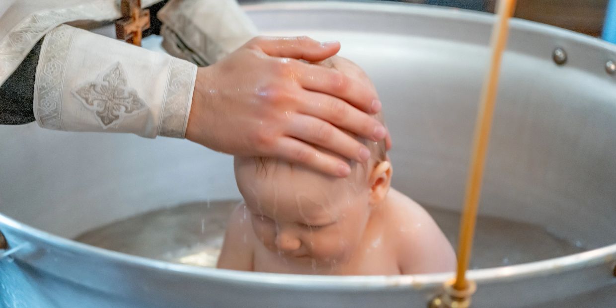 A baby being baptized with water poured on their head.