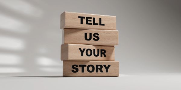 Wooden blocks spelling 'TELL US YOUR STORY.'