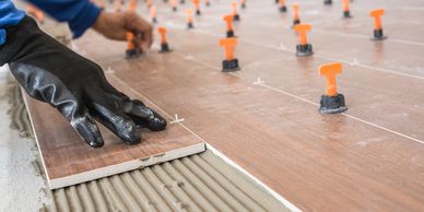 Person installing floor tiles with spacers.