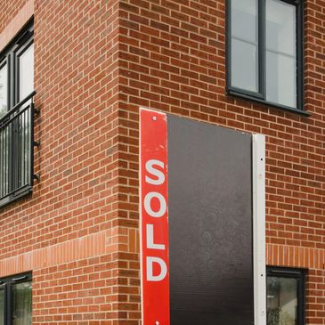 A brick building with a sold sign on the corner.