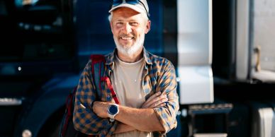 Smiling truck driver standing with arms crossed.