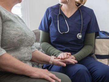 A nurse comforting a patient by holding her hands.