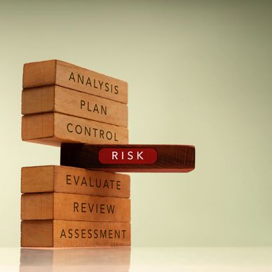 Wooden blocks labeled with risk management steps, highlighting 'RISK' in red.