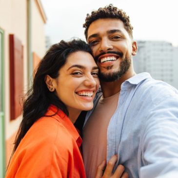 Smiling couple taking a selfie outdoors.