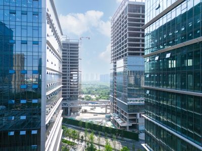 Modern glass office buildings framing a bright cityscape with greenery.