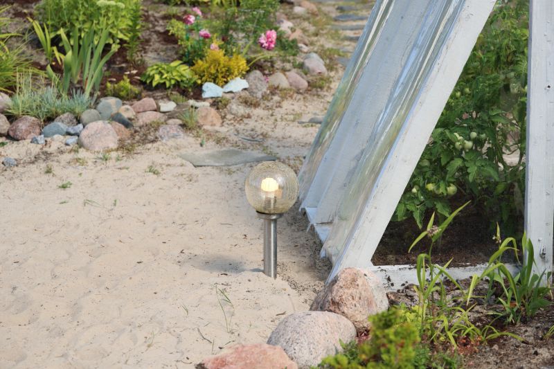 A stunning and beautiful garden scene showcasing a decorative solar globe light surrounded by lush, vibrant foliage