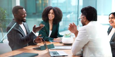 Diverse coworkers happily discussing at a meeting.